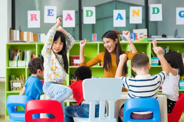 Happy Asian female OT and mixed-race kids in classroom