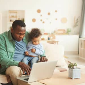 Dad holding small child while receiving telehealth services