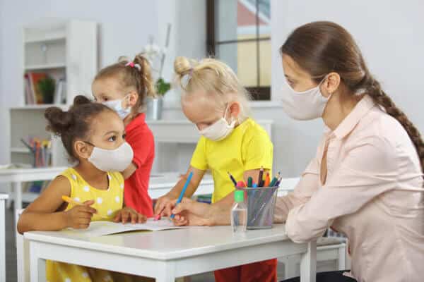 A therapist and children wearing masks in a classroom during COVID-19 quarantine