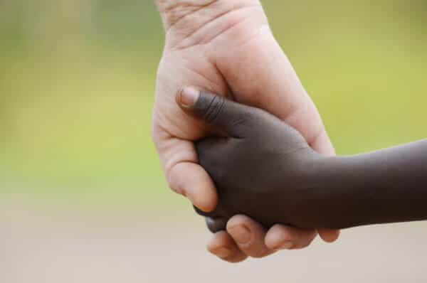 adult and child of different races holding hands
