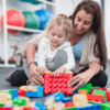 Therapist working with small child and jumbo Lego blocks