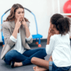 Therapist mirroring mouth positions for pronouncing sounds with a young child