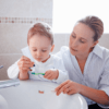 Mother and young child at the bathroom sink practicing how to brush teeth