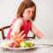 Young child pushing a plate of food away from herself