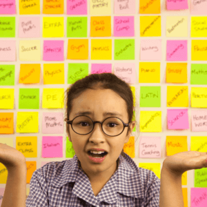 Young child in the foreground with her hands lifted in confusion against a background of Post-it notes