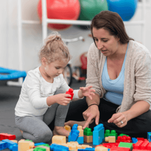 Adult and young child playing with jumbo Lego blocks on the floor