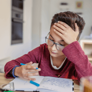 Small child with hand over his forehead struggling with writing correctly